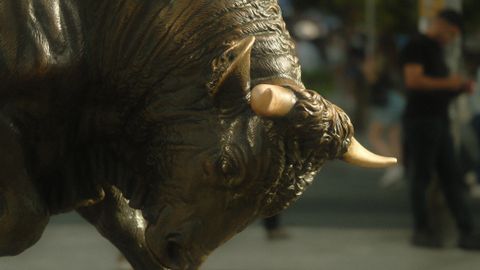 Powerful bronze bull statue on urban street capturing strength and tradition.