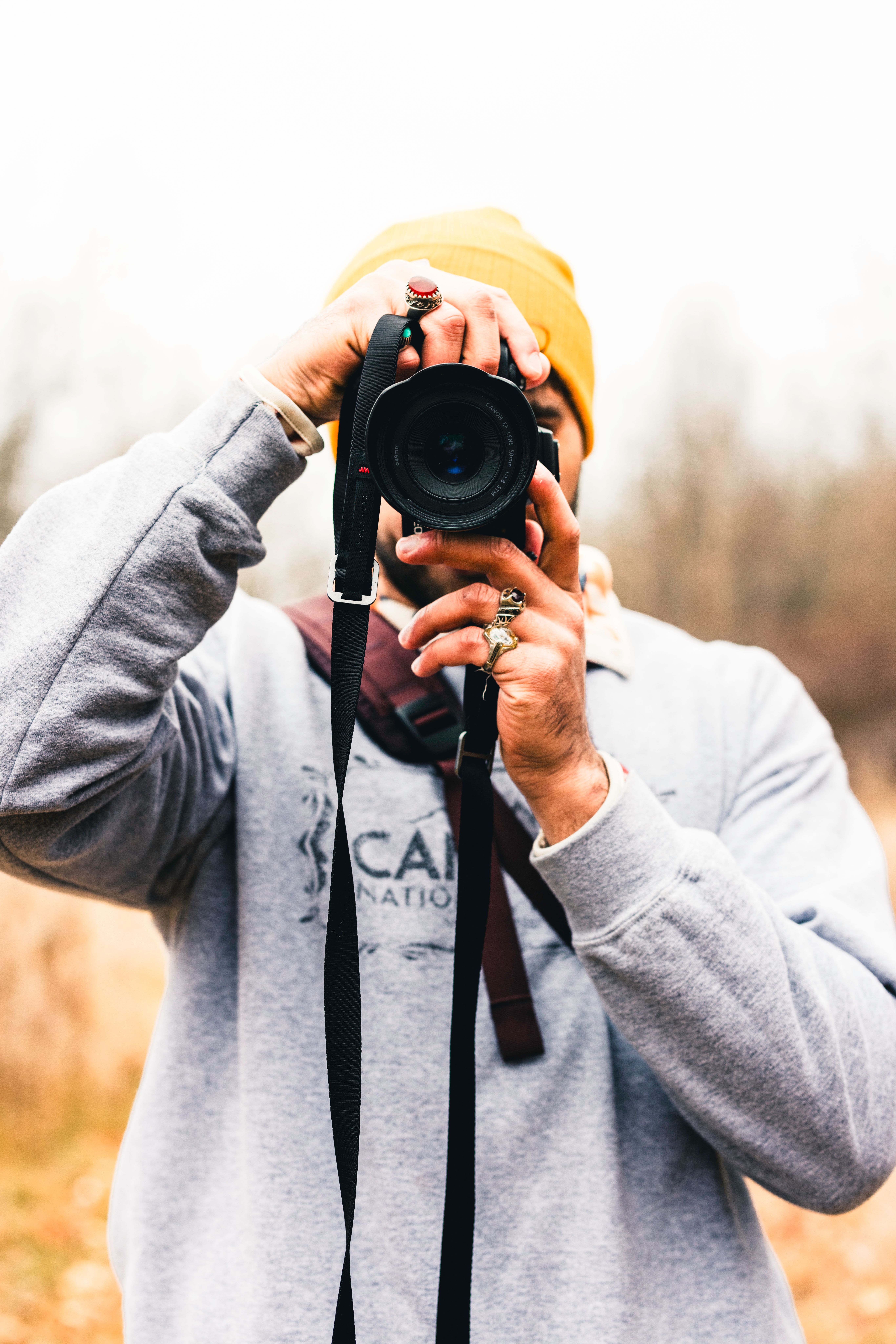A photographer captures the beauty of an autumn forest while wearing a beanie.