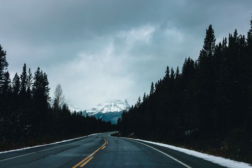Free A serene winter road cutting through the snow-capped Rockies in Glacier, BC, Canada. Stock Photo