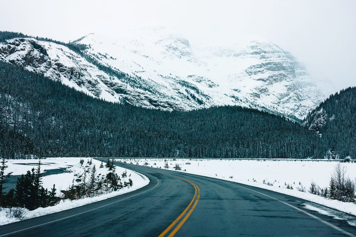 A picturesque winter road winding through a snowy mountain landscape in Glacier, British Columbia, Canada. Illustrative editorial photograph.