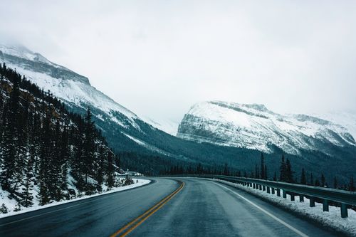 Free Breathtaking winter view of a winding road in Glacier, BC, surrounded by snow-covered mountains. Stock Photo