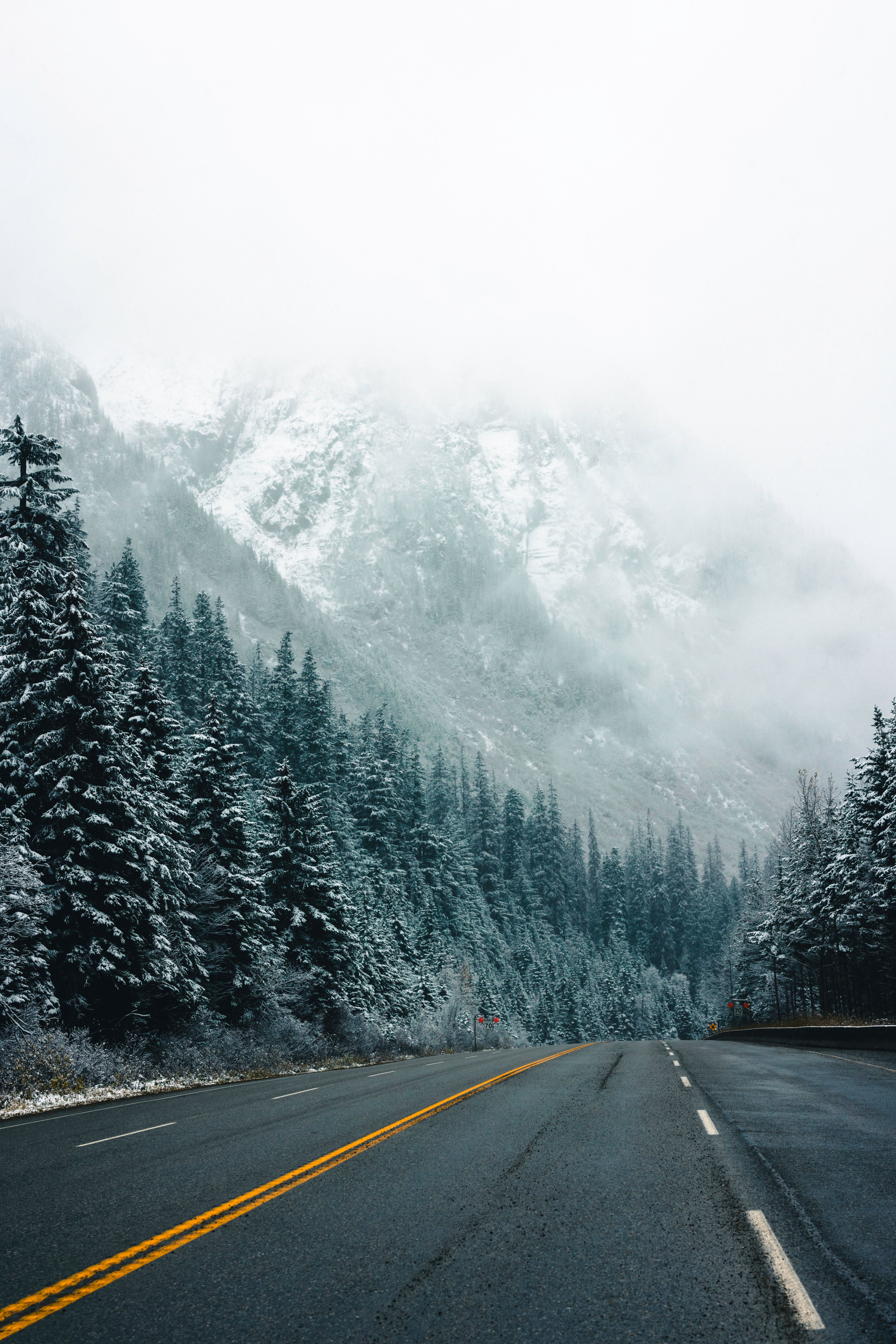 Shuttle bus parked near a mountain road in Glacier National Park with alpine peaks and evergreen trees