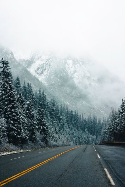 Shuttle bus parked near a mountain road in Glacier National Park with alpine peaks and evergreen trees
