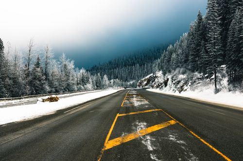 Free Scenic winter road cutting through snowy forest in Glacier, BC, Canada, capturing tranquility and adventure. Stock Photo