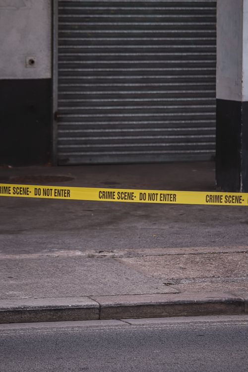 Free Urban crime scene marked with yellow police tape outside a garage. Stock Photo