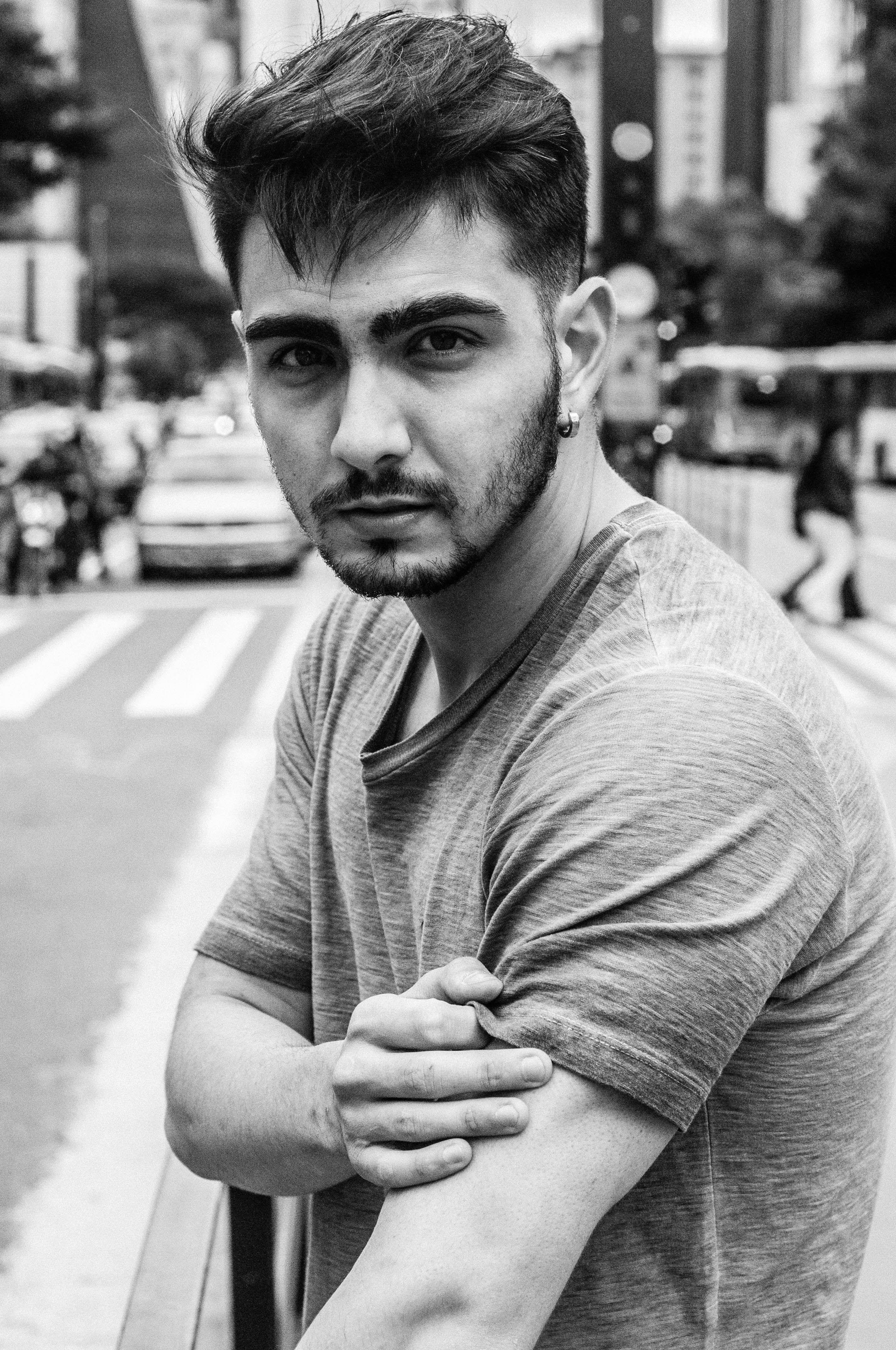 Black and white portrait of a tattooed man in a city street, showcasing urban style.
