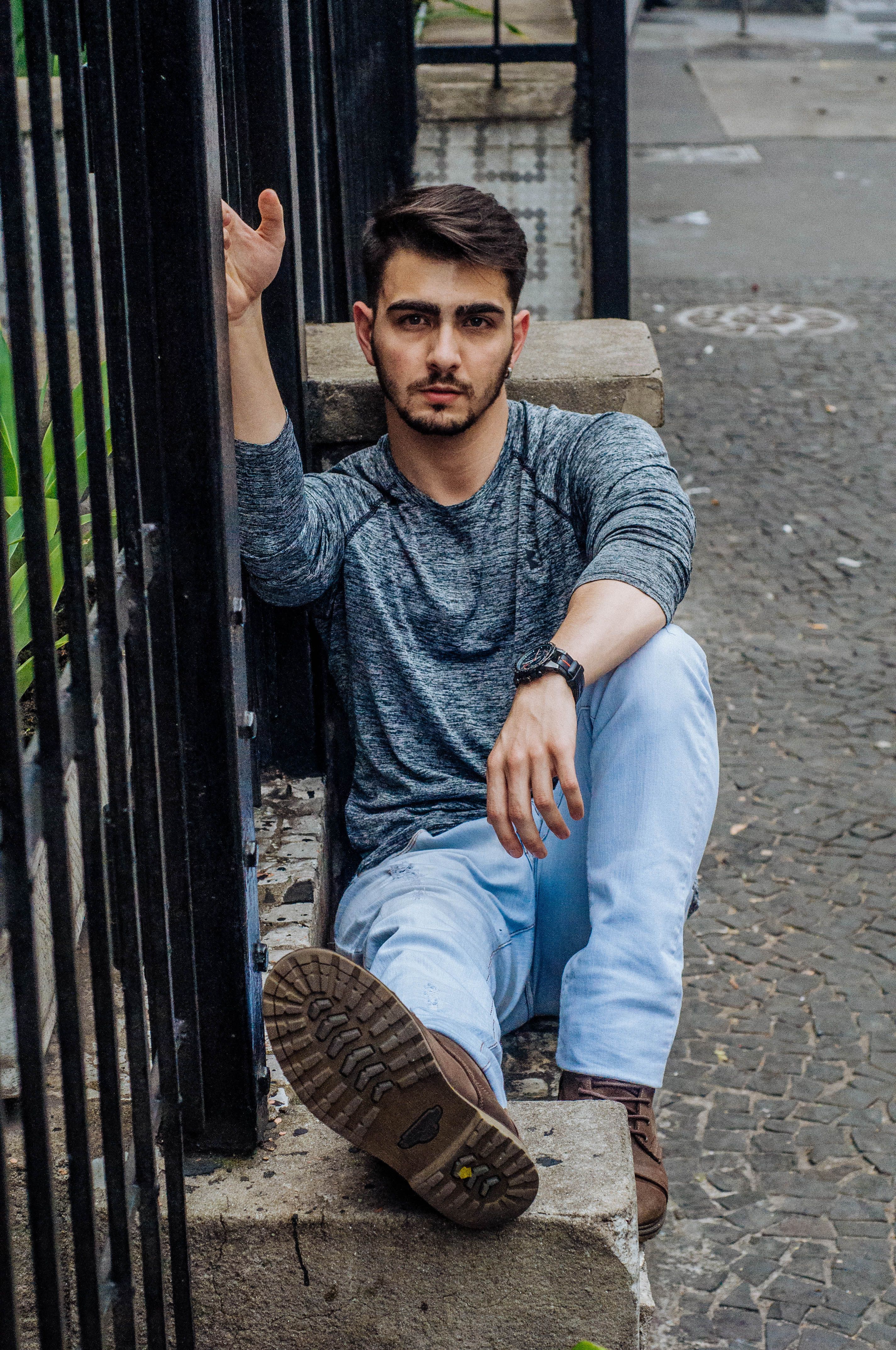A casual portrait of a tattooed man sitting outdoors, showcasing urban fashion and style.