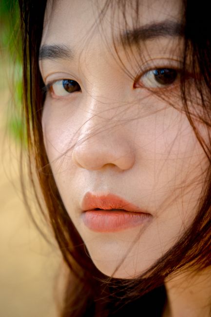 Intimate close-up portrait of a woman with natural makeup and tousled hair. Soft and expressive gaze.