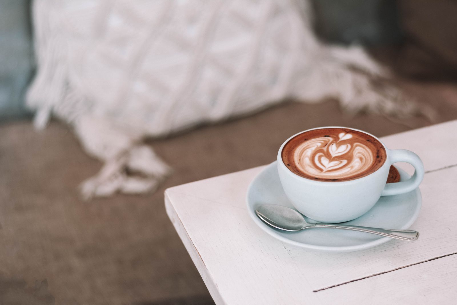 Latte with beautiful art in cozy café setting, perfect for morning relaxation.