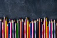 在黑板背景上，排列着用于艺术项目的彩色铅笔，充满活力