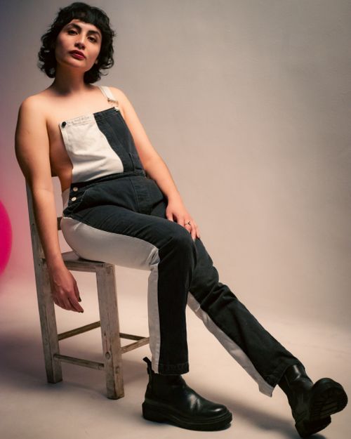 Free Fashion portrait of a woman in black and white overalls, sitting on a chair, Ciudad de México. Stock Photo
