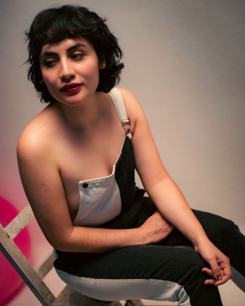 Free Woman in overalls sitting indoors, with a thoughtful expression, in a relaxed setting in Ciudad de México. Stock Photo