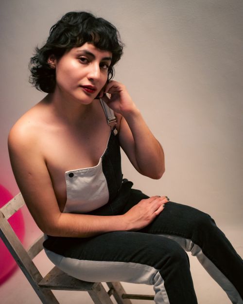 Free Expressive portrait of a woman in stylish overalls, exuding confidence and modern fashion. Stock Photo