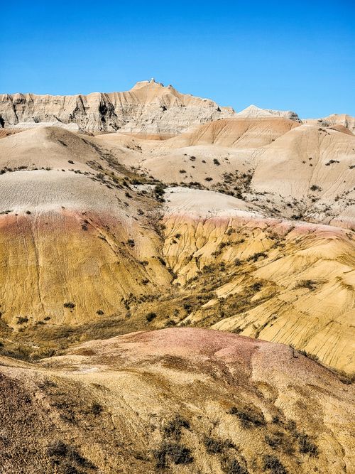 Free A vibrant view of colorful, layered hills in an arid, desert landscape under a blue sky. Stock Photo