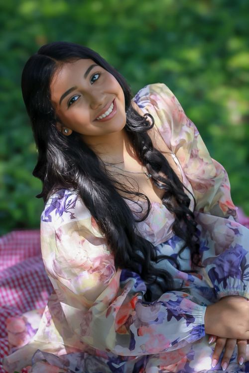 Free Smiling woman in a floral dress sitting outdoors in sunny Honduras. Stock Photo