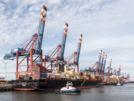 Container ship docked at Port of Hamburg, cargo cranes visible.