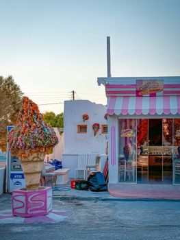 Colorful ice cream shop in Fira with a giant cone display and Greek architectural style.