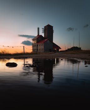 Scenic view of sunlit historic building reflected in water at sunrise in Szklarska Poręba, Poland.