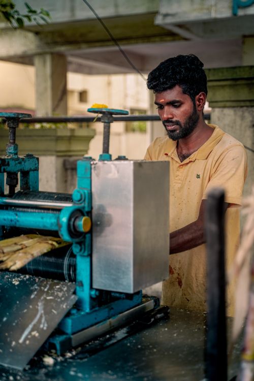 Free A man working at a street-side sugarcane juice machine in Chennai, India. Stock Photo