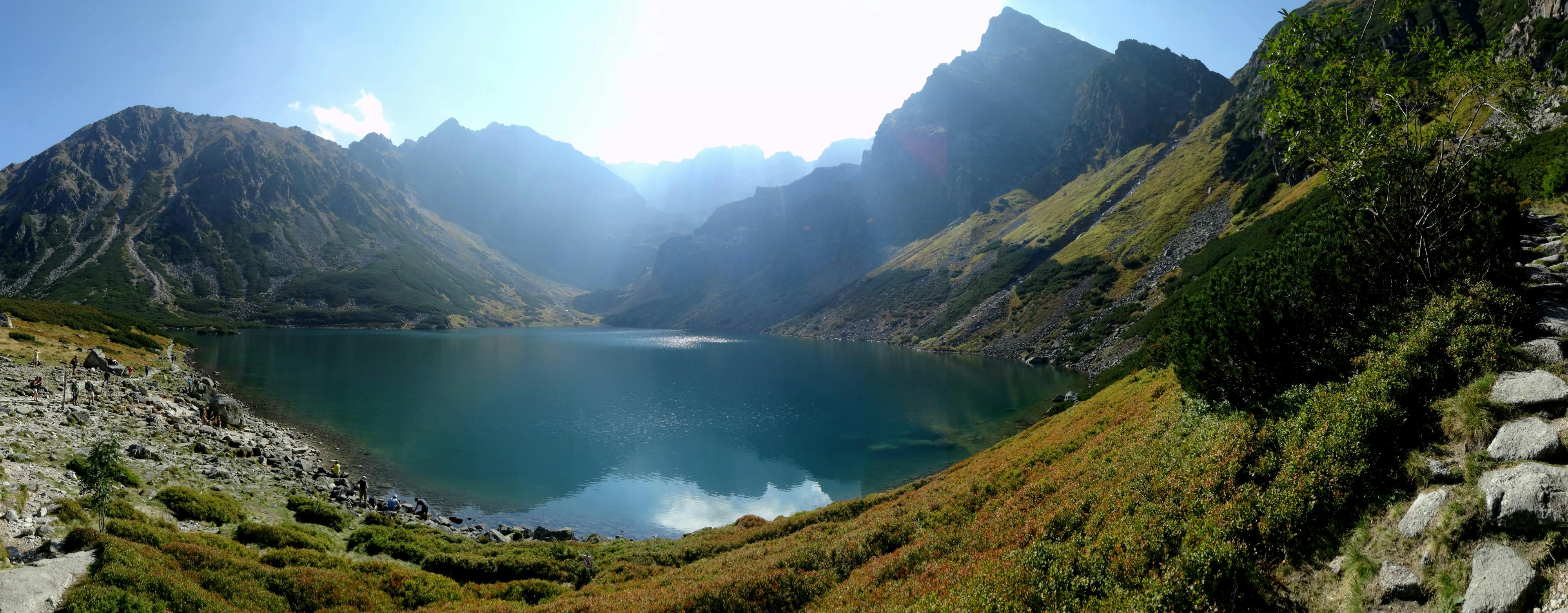 壮丽的山峰环绕着宁静的山湖，阳光洒满全景