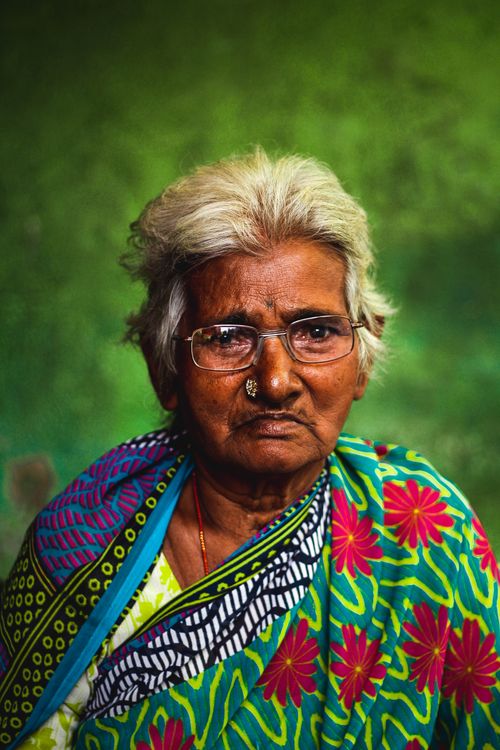 Free Senior woman in vibrant saree against green background, depicting traditional Indian culture. Stock Photo