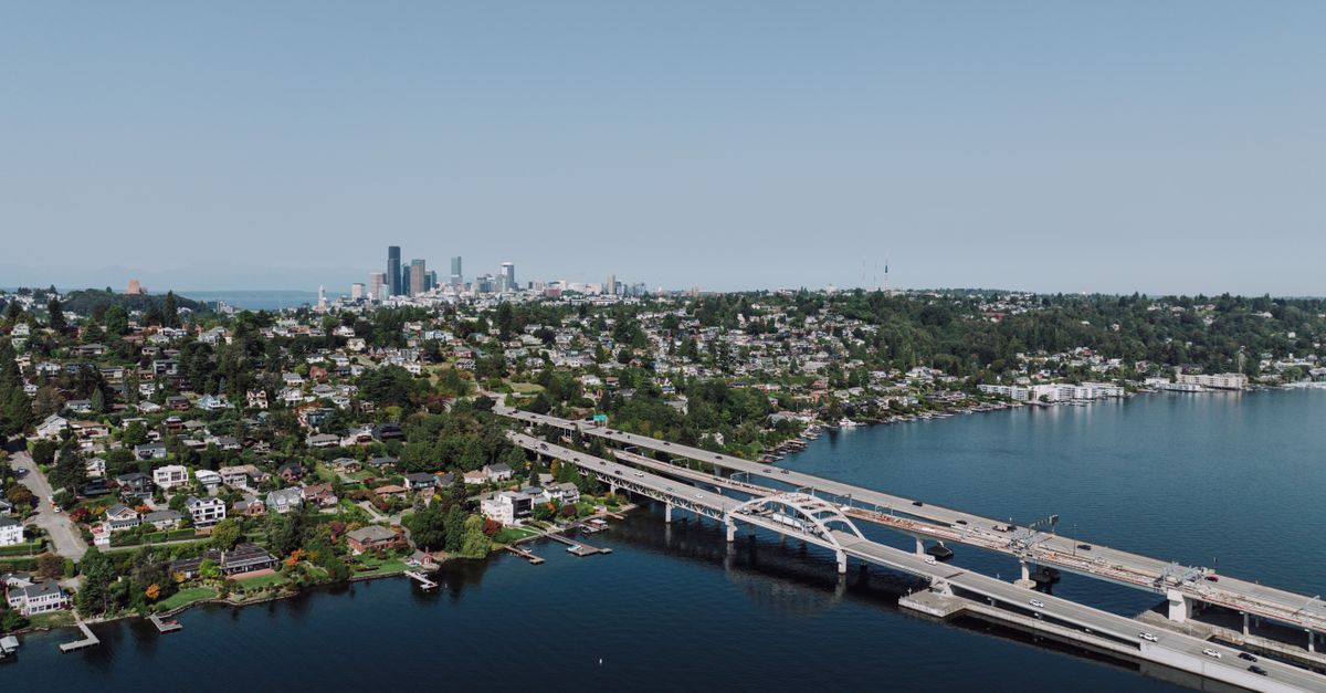 Scenic aerial shot of Seattle skyline with bridge spanning across a lake on a clear day.