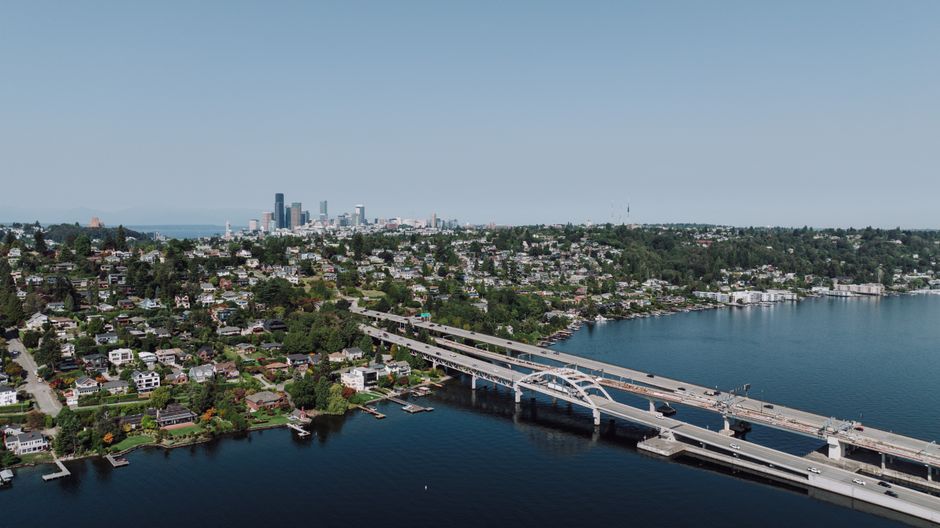 Scenic aerial shot of Seattle skyline with bridge spanning across a lake on a clear day.