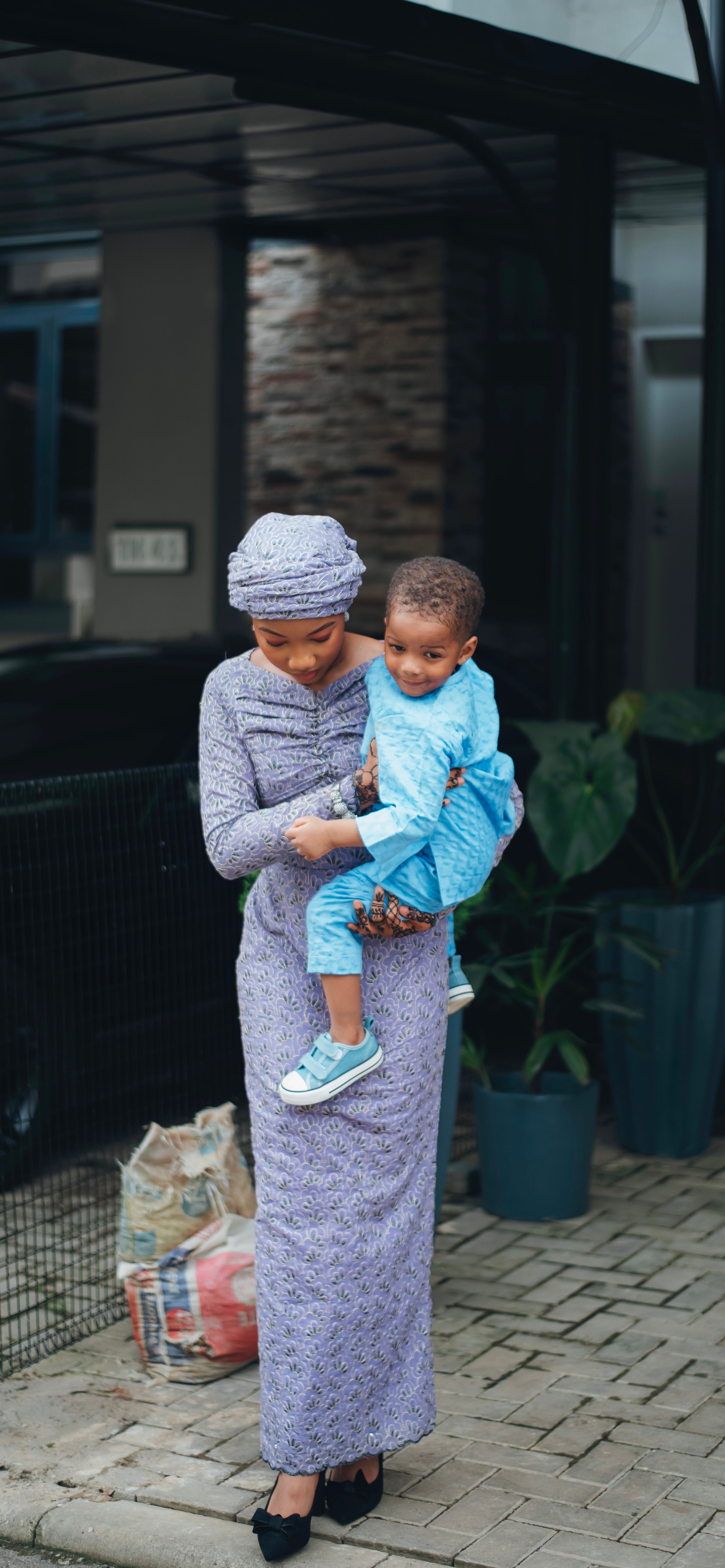 A woman in a traditional dress carries her child outside a building.