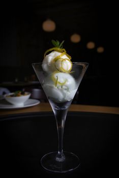 Lemon sorbet elegantly presented in a glass with lemon zest and mint garnish.