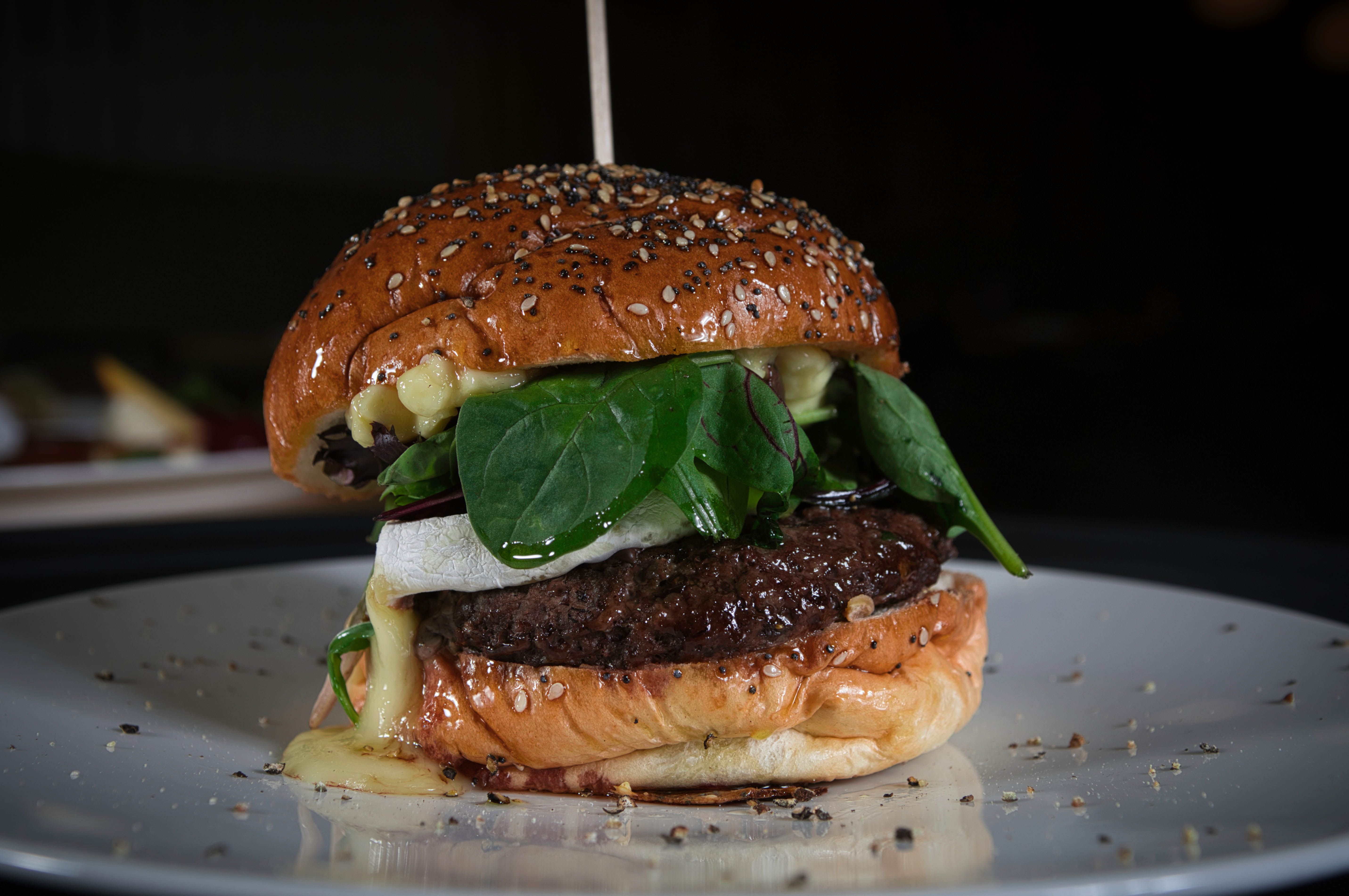 A mouthwatering gourmet burger with fresh spinach and sesame seed bun.