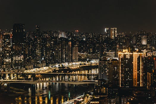 A breathtaking view of a cityscape at night with illuminated skyscrapers and reflections on the river.
