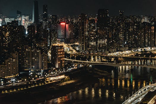 A vibrant aerial view of a bustling city illuminated at night, showcasing skyscrapers and bridges.
