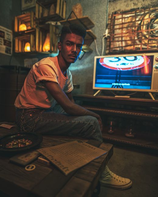 Man sitting in a vintage-styled room watching television, captured in warm tones.