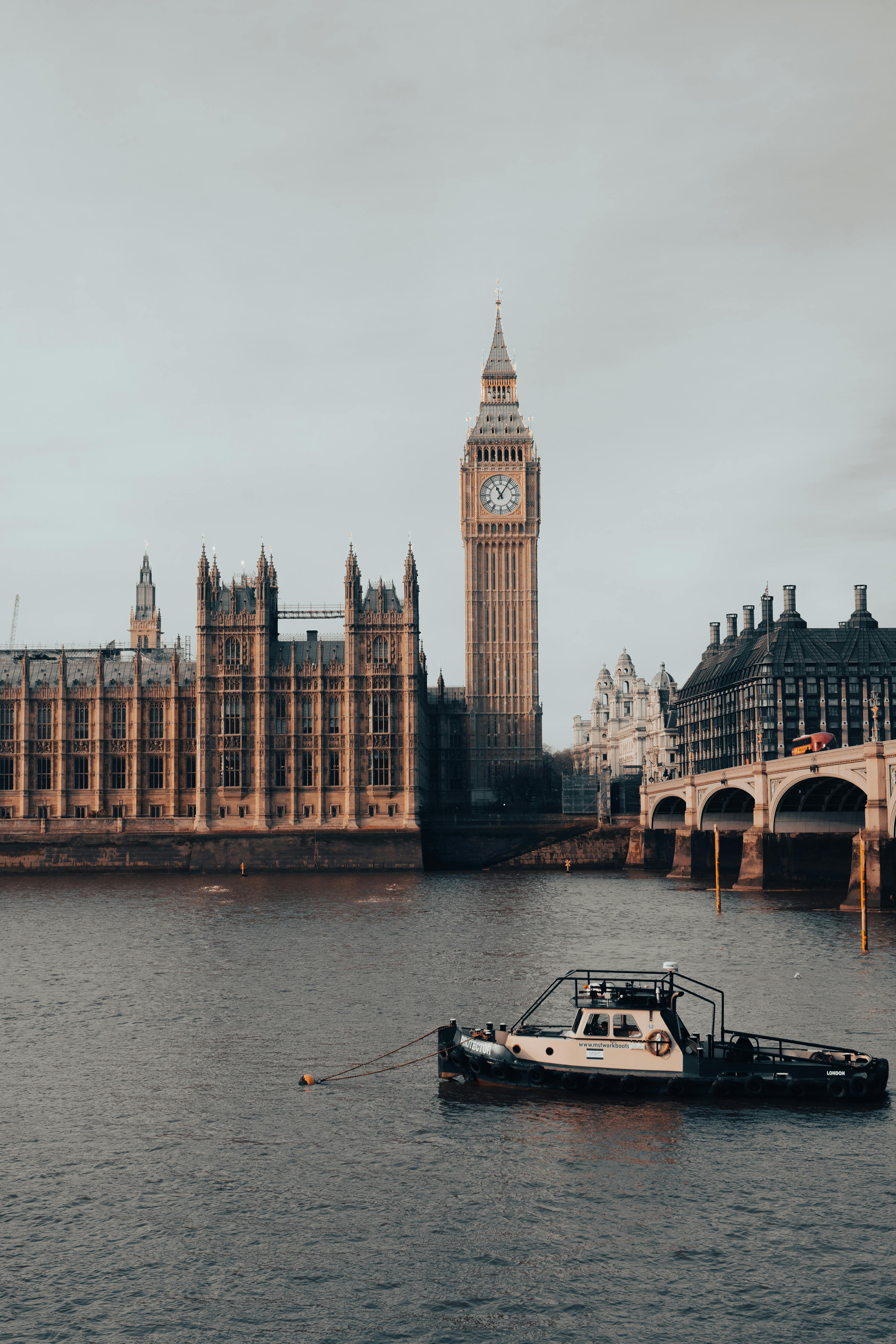 Iconic view of Big Ben and the River Thames in London with a boat in the foreground.