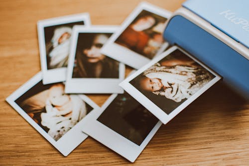 Free A collection of instant photo prints scattered on a wooden table, featuring personal moments. Stock Photo