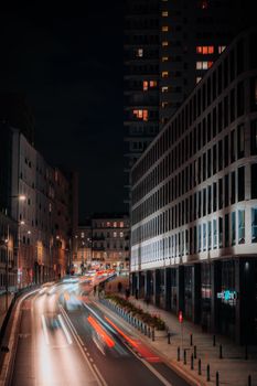 Vibrant city street at night in Warsaw, showcasing dynamic urban life with light trails.