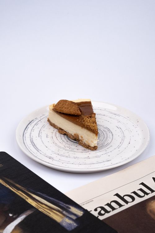 Free Biscuit cheesecake slice on artistic plate with newspaper background. Stock Photo