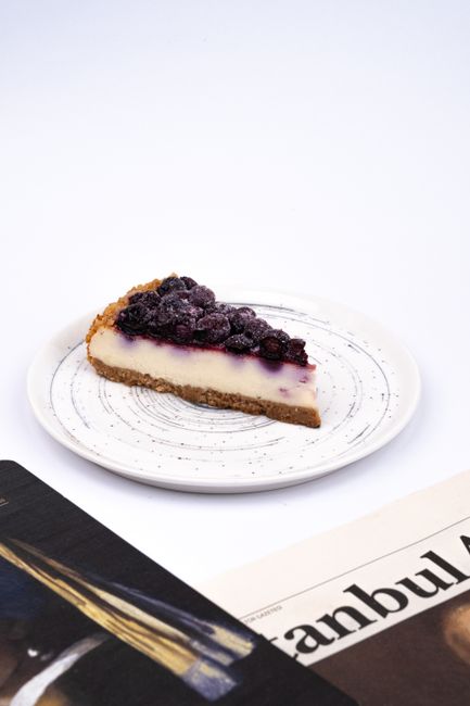 Slice of cheesecake topped with mixed berries on a white plate.