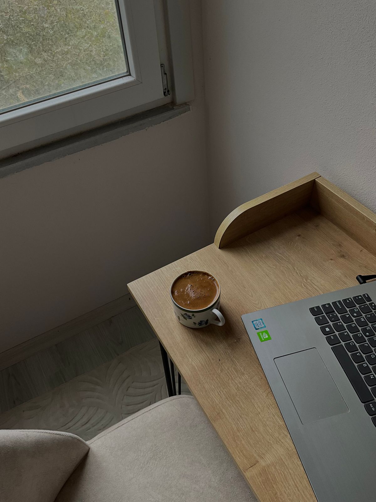 柔らかい光の中でノートPCとコーヒーが置かれたデスクの様子