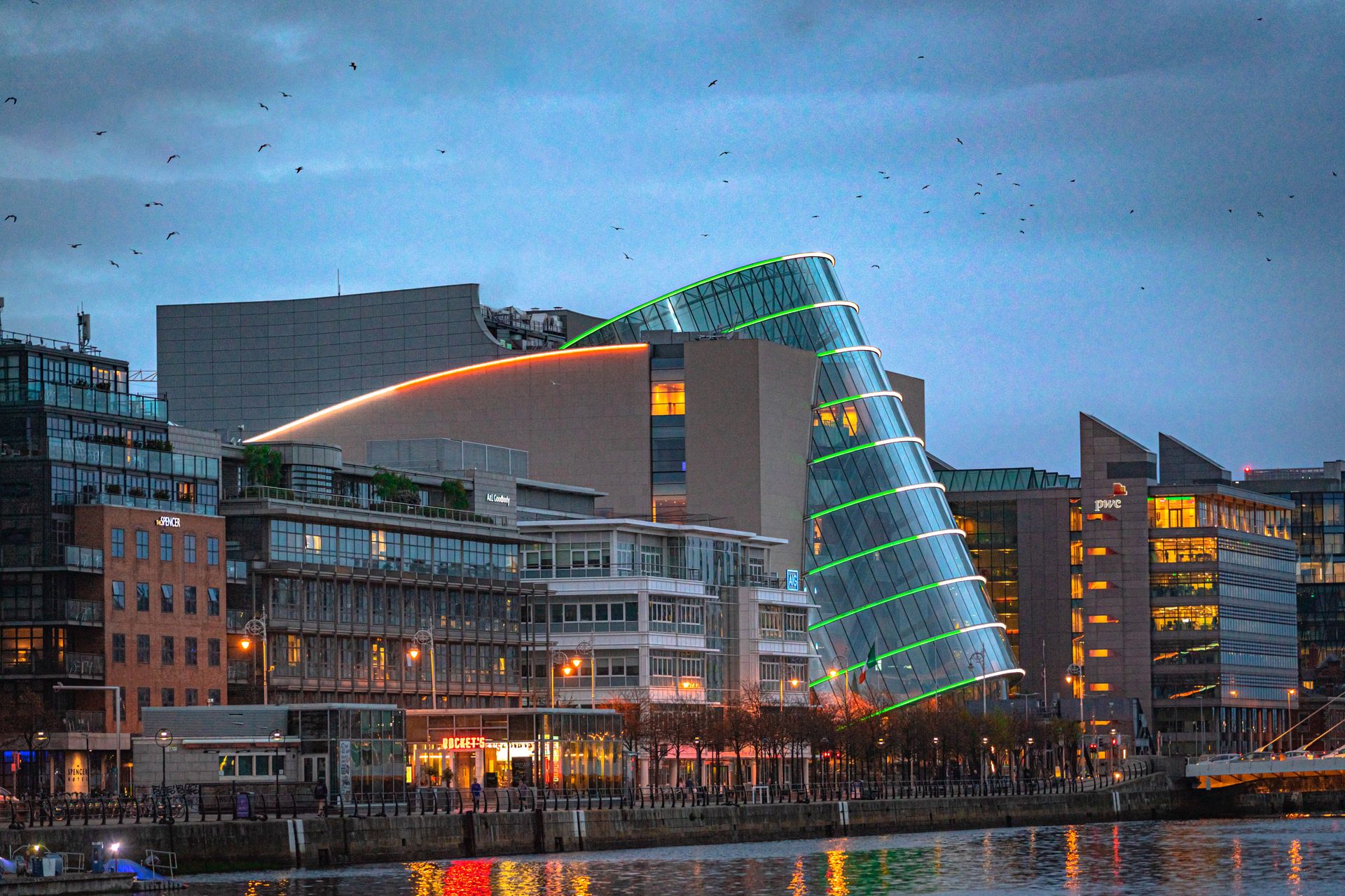 A stunning night view of the Dublin Convention Centre by the River Liffey, illuminated in vibrant colors.