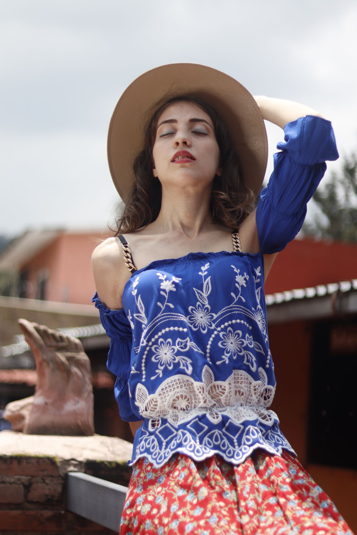 Woman in an embroidered blue top and wide-brim hat