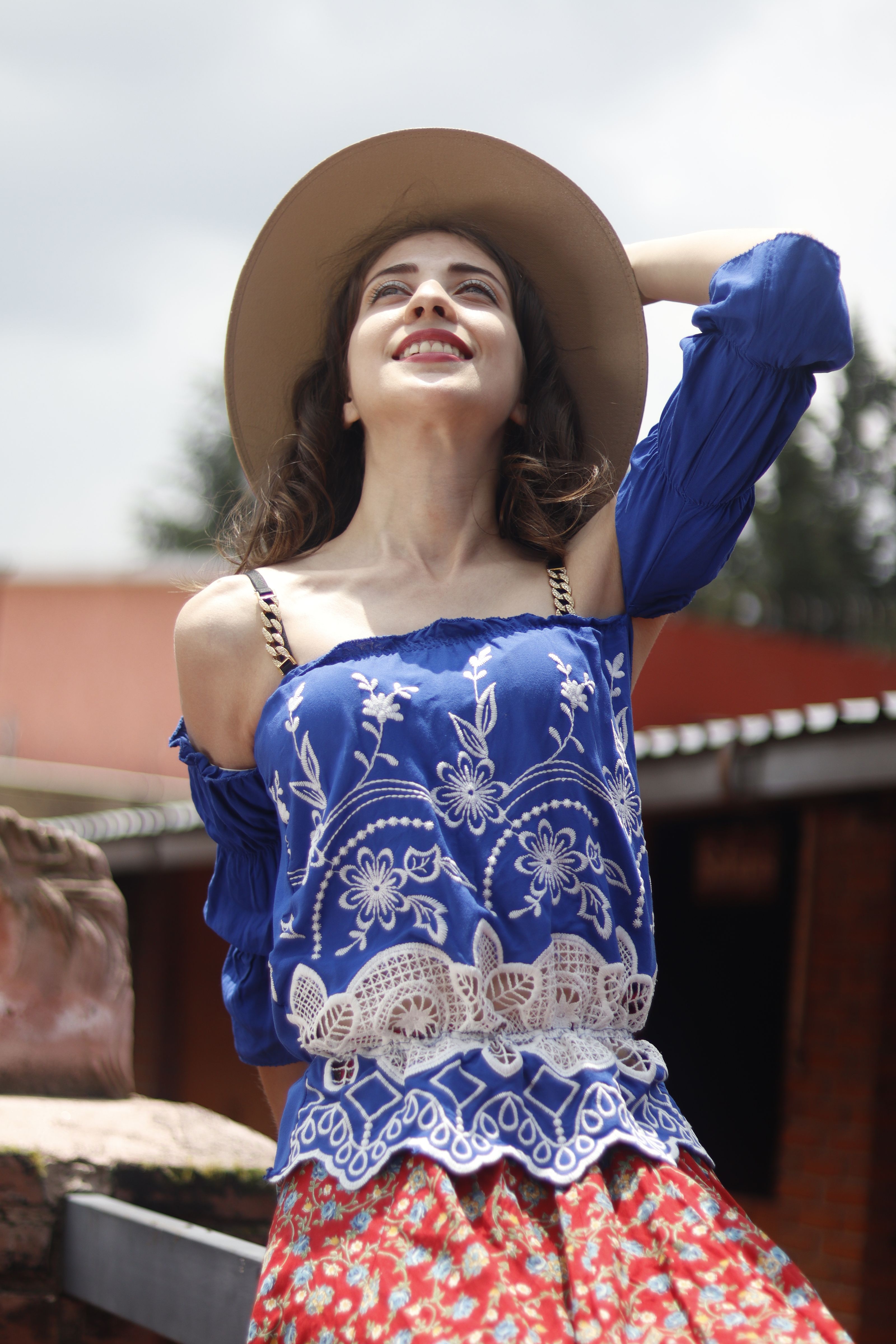 Uma mulher sorridente com trajes boêmios vibrantes aproveita um dia ensolarado ao ar livre, transmitindo felicidade e liberdade.