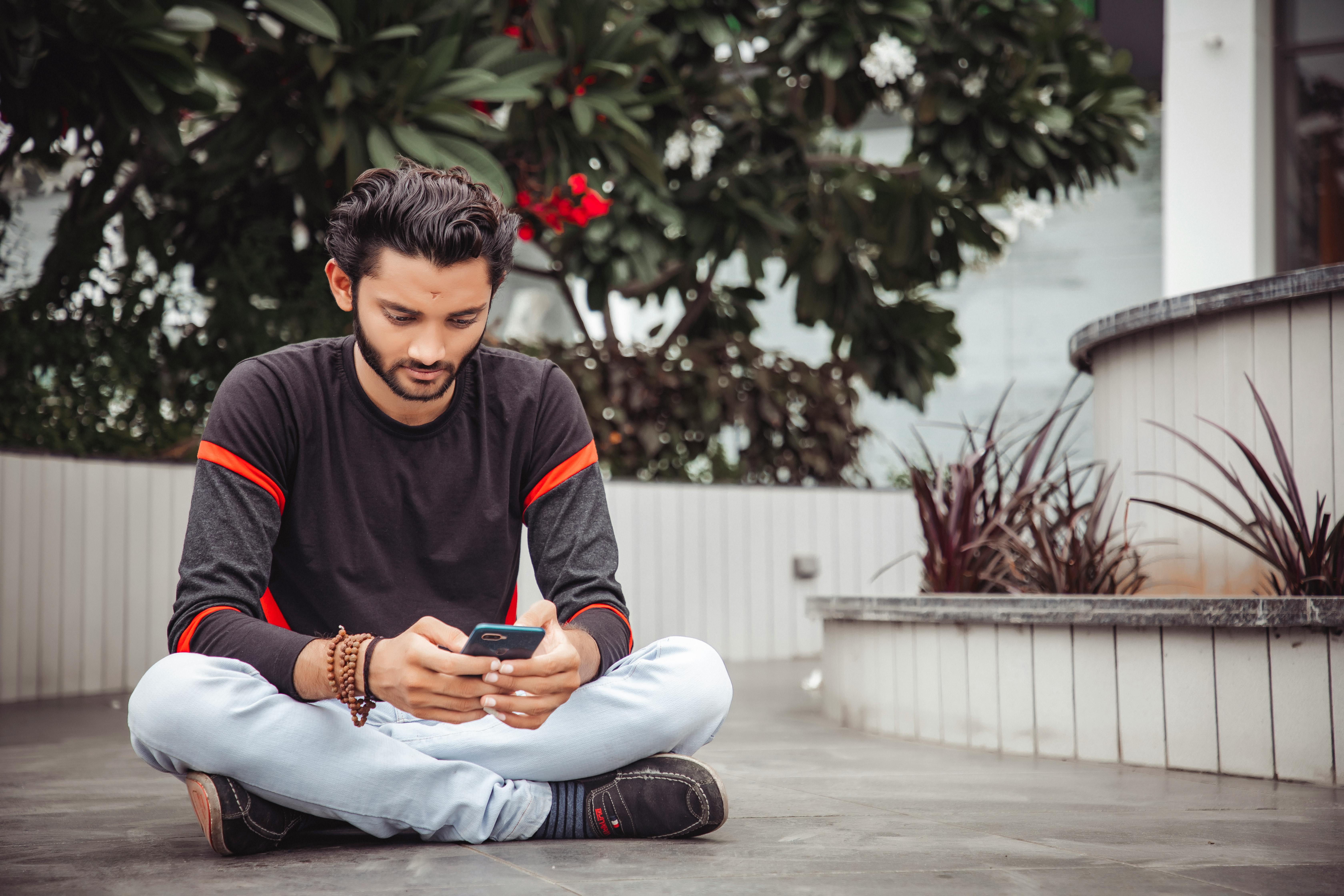 Man Wearing Black Long Sleeved Shirt Holding Blue Smartphone