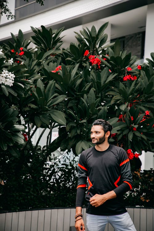 Foto Van Man Poseren Terwijl Wegkijken Met Boom Op De Achtergrond