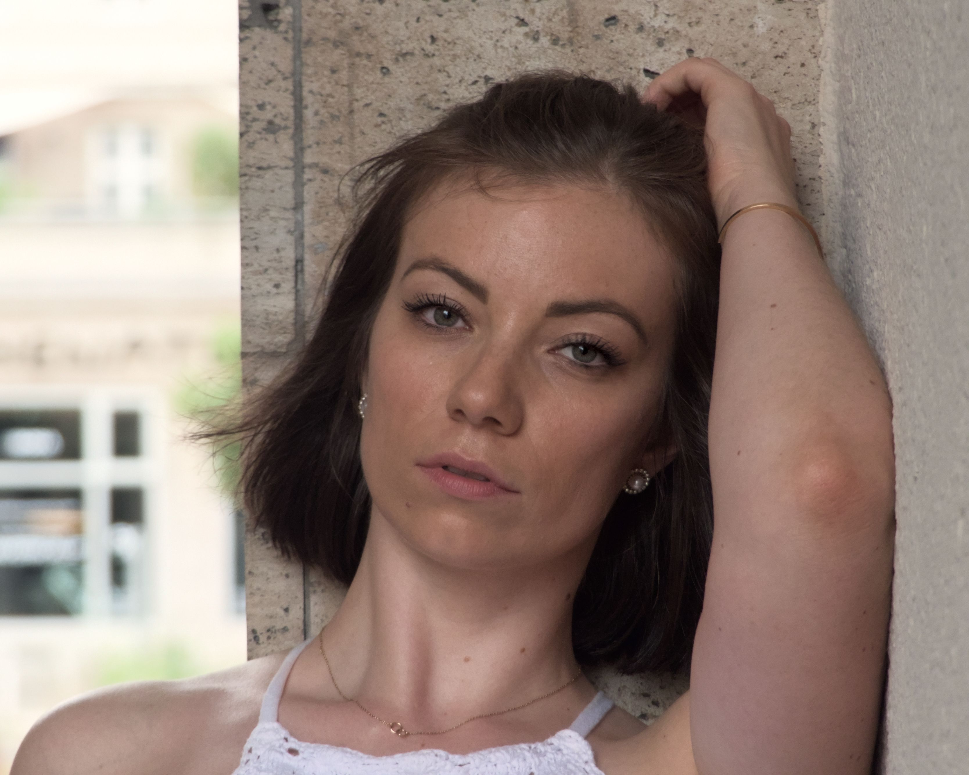 Stylish close-up portrait of a woman leaning against a stone wall in Berlin.