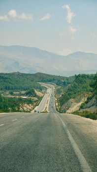 Long road stretching through mountain landscape on a clear summer day.