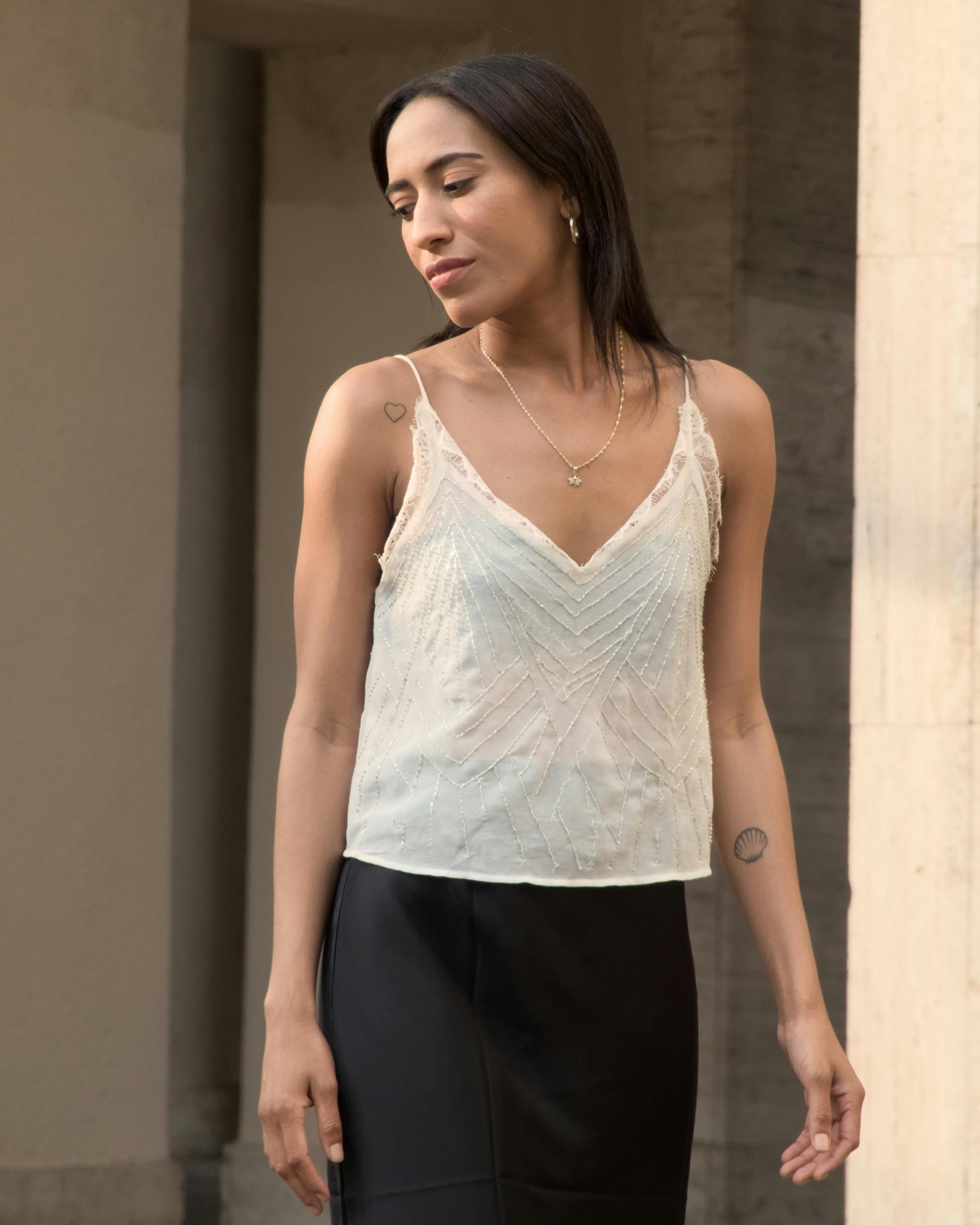 A fashionable woman in a light top and skirt poses gracefully against Berlin architecture.