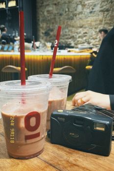 Two iced drinks and a vintage camera on a table in a stylish cafe.
