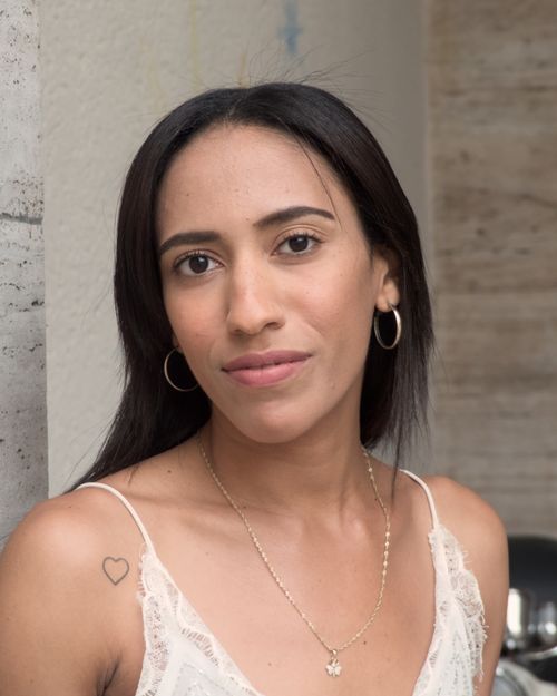 Free Elegant woman with hoop earrings and a lace top posing against a wall in Berlin. Stock Photo