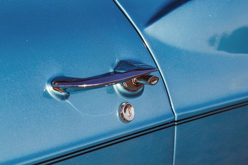 Free Detailed shot of a shiny chrome handle on a vintage blue car door, capturing classic design. Stock Photo